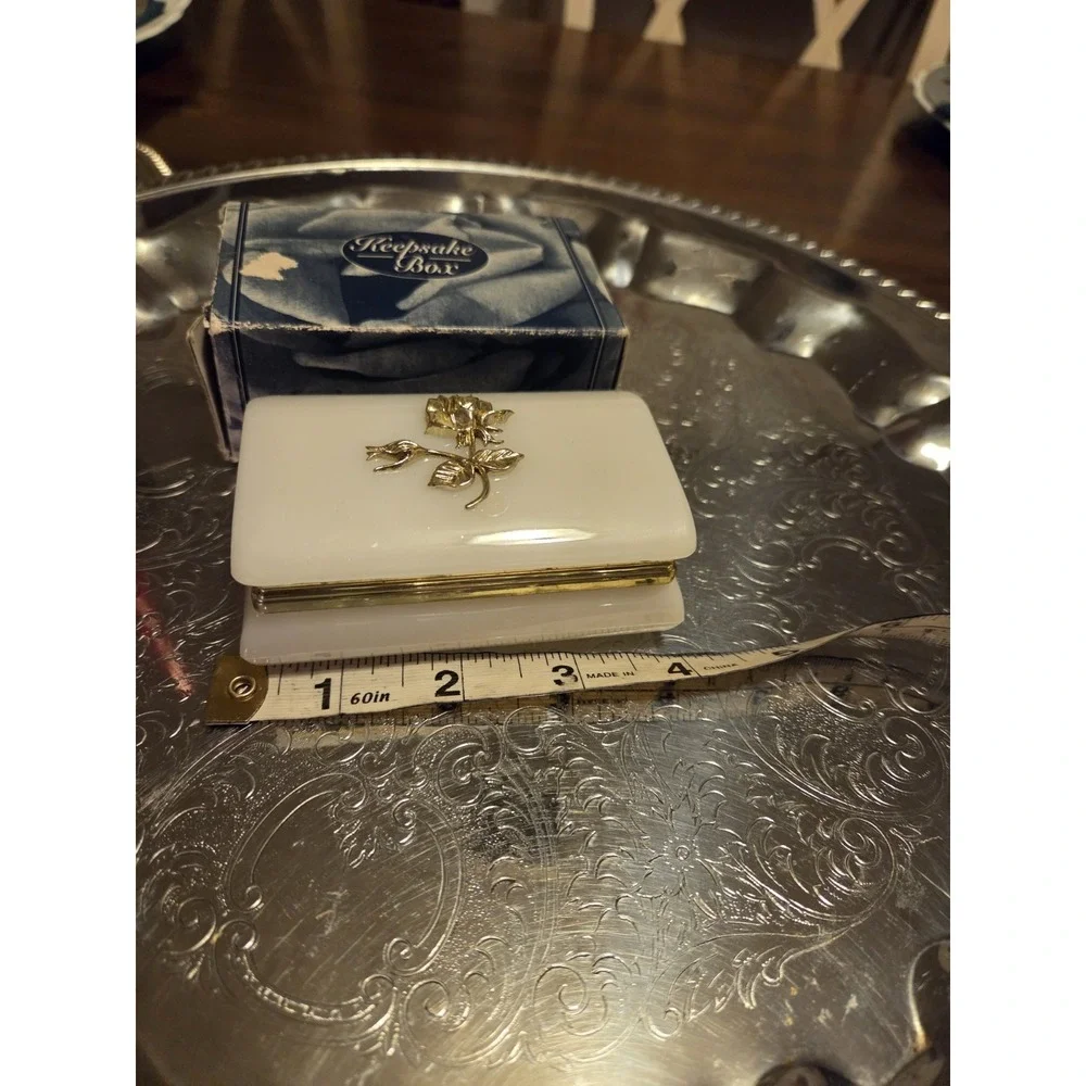vintage white hinged trinket box features a polished finish with a delicate,...